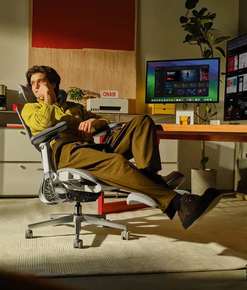 Man reclined with crossed legs in the HBADA E3 Pro beside his desk
