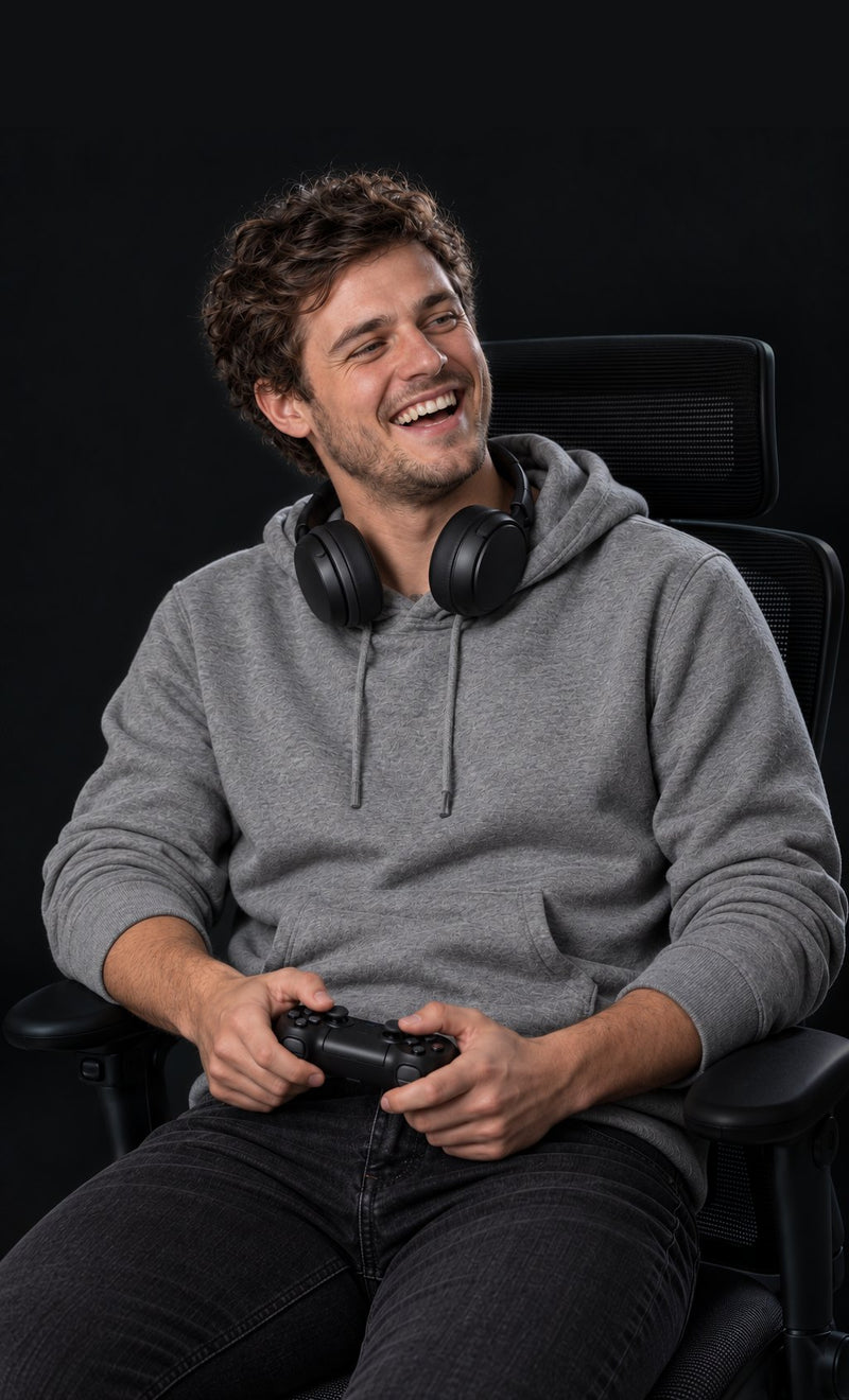 Man with a game controller, seated in an ergonomic chair